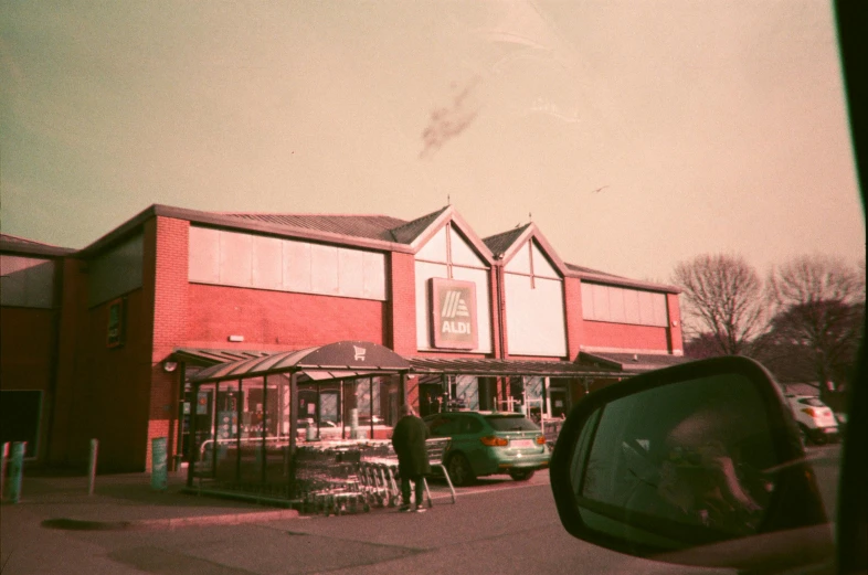 a person standing in front of a red building, a polaroid photo, by Andrew Allan, altermodern, stood in a supermarket, hulton archives, grainy vintage, mcdonald