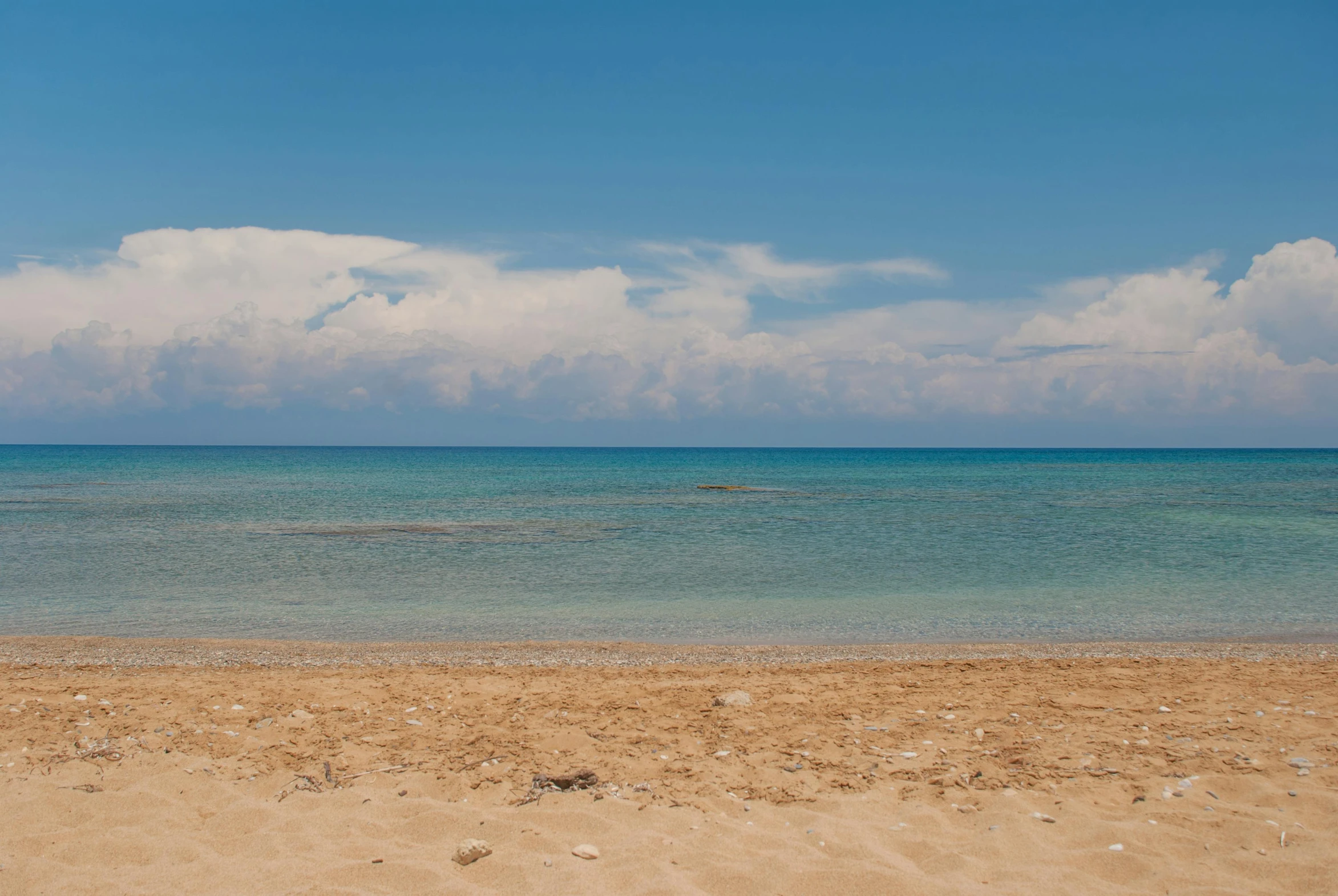 a large body of water sitting on top of a sandy beach, by Constantine Andreou, unsplash, john pawson, greek, under blue clouds, studio photo