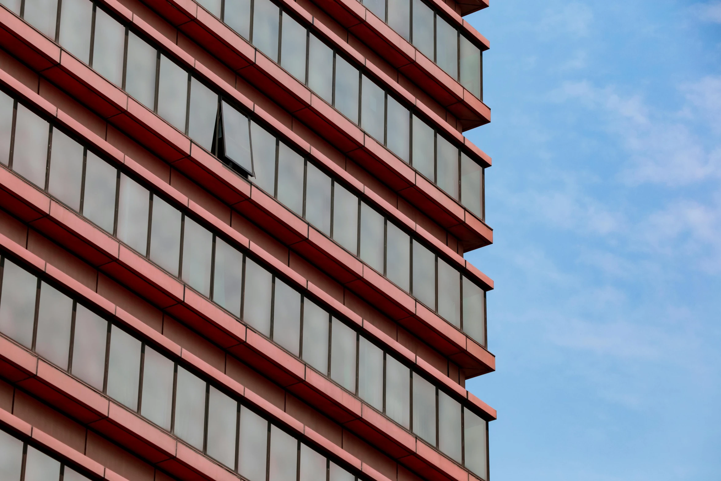 a clock on the side of a tall building, a photo, inspired by Richard Wilson, unsplash, brutalism, venetian red, seen from a distance, slide show, steel window mullions