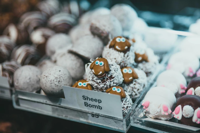 a display case filled with lots of doughnuts, a tilt shift photo, by Julia Pishtar, pexels contest winner, sheep, bombs, closeup of an adorable, chocolate