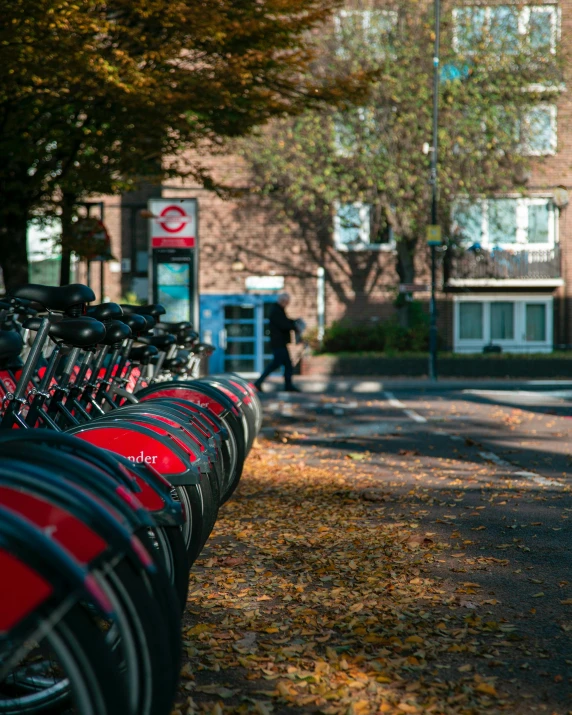 a row of bikes parked on the side of a road, by Adam Rex, unsplash, happening, red and black colour scheme, schools, during autumn, kings row in the background