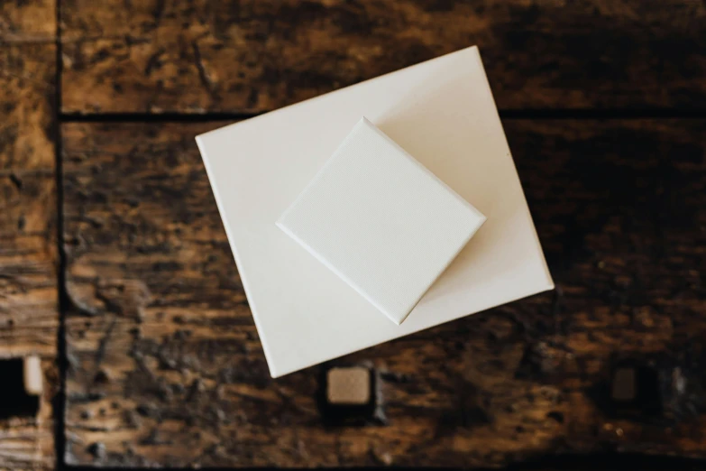 a white box sitting on top of a wooden table, unsplash, square, various sizes, ivory, small