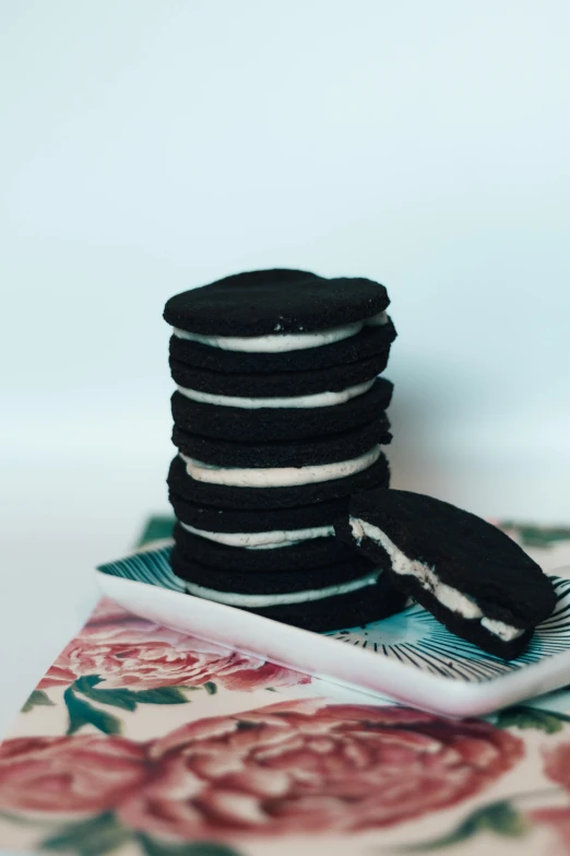 a stack of cookies sitting on top of a plate, a black and white photo, by Winona Nelson, unsplash, made of smooth black goo, licorice allsort filling, white stripes all over its body, product display photograph