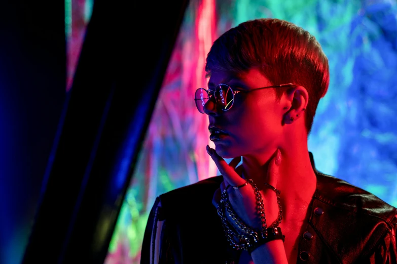 a man wearing glasses and a leather jacket, by Julia Pishtar, trending on pexels, bauhaus, psychedelic lighting, pixie cut with shaved side hair, vivid lighting, hunting