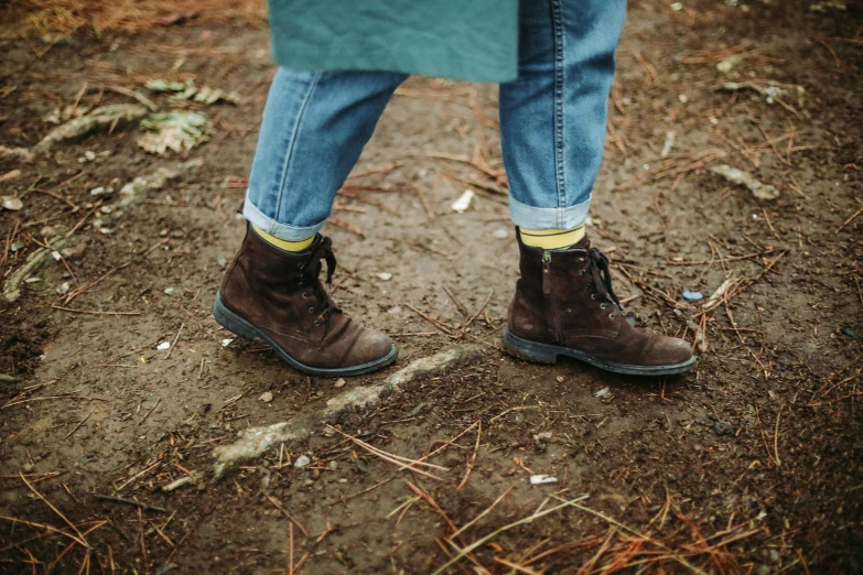 a person wearing blue jeans and brown boots, by Jessie Algie, unsplash, yellow details, in the wood, green and brown clothes, dressed in a worn
