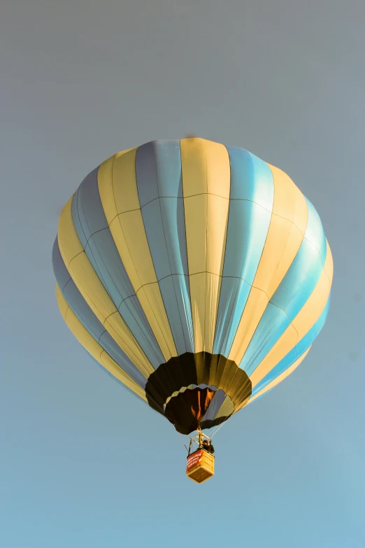 a yellow and blue hot air balloon flying in the sky, by Dave Melvin, happening, late afternoon, light-blue, close-up photo, high-angle