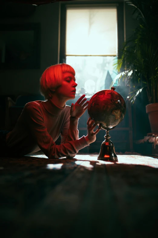 a woman sitting at a table looking at a globe, inspired by Elsa Bleda, magical realism, beeple and tim hildebrandt, girl with short white hair, red and cinematic lighting, occult aesthetics alchemy