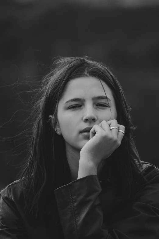 a black and white photo of a woman smoking a cigarette, a black and white photo, unsplash contest winner, realism, portrait of normal teenage girl, windblown dark hair, sittin, heart shaped face