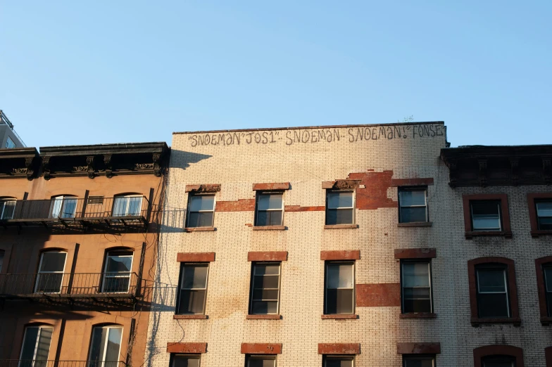 a building with a sign on the side of it, by Joel Shapiro, unsplash, graffiti, harlem, ignant, sunny morning light, simon lee