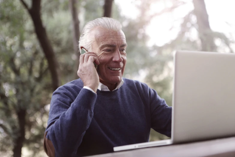a man sitting in front of a laptop talking on a cell phone, old man, selling insurance, lush surroundings, avatar image