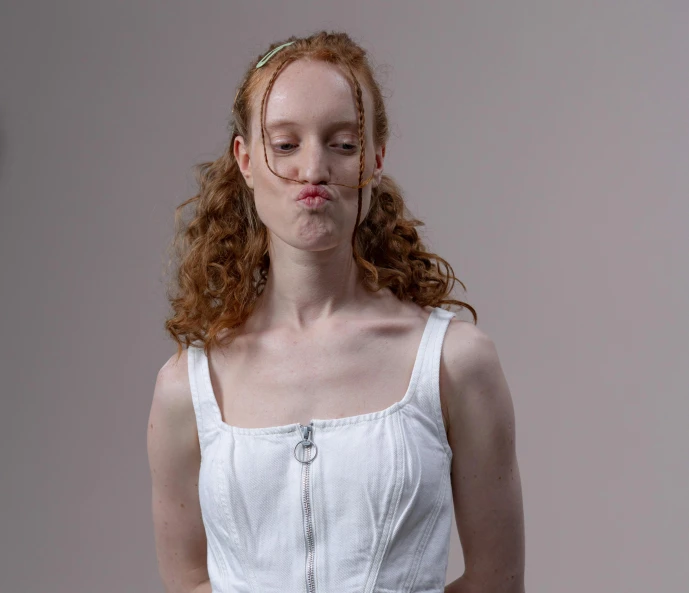 a woman with red hair wearing a white dress, inspired by Anna Füssli, licking out, wearing a vest top, long hook nose, in front of white back drop