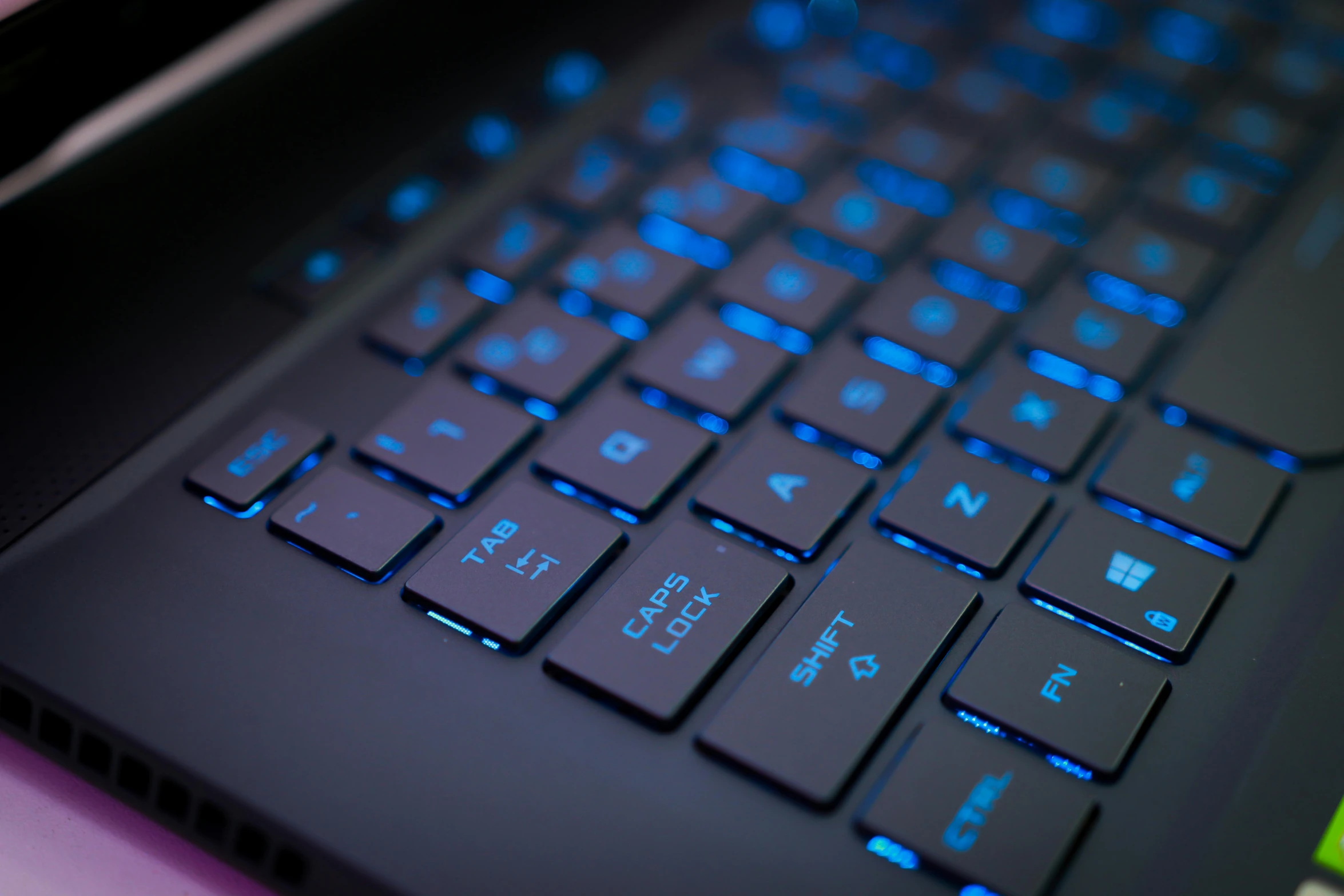 a close up of a laptop keyboard on a table, a computer rendering, by Julia Pishtar, unsplash, computer art, blue leds, video game texture, low - angle shot, neon edges on bottom of body