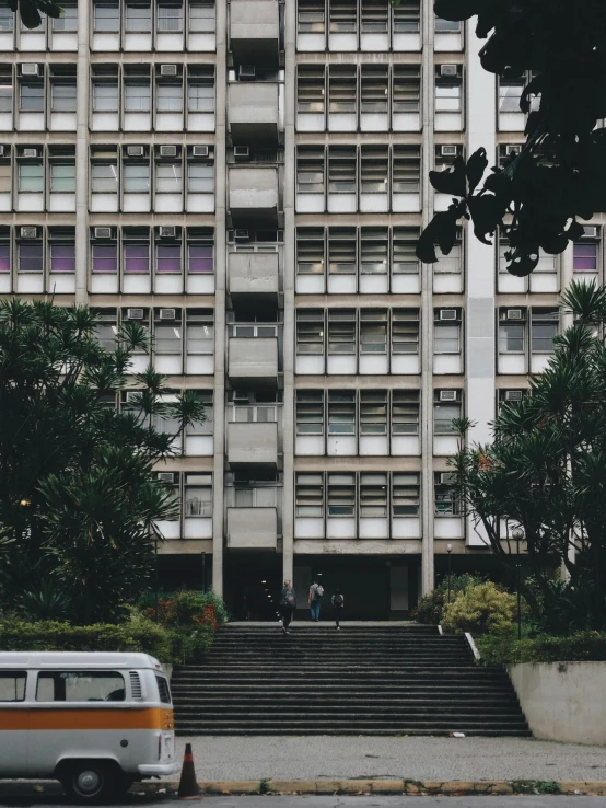 a van parked in front of a tall building, inspired by Thomas Struth, unsplash contest winner, brutalism, 1970s philippines, exterior view, schools, 😭 🤮 💕 🎀