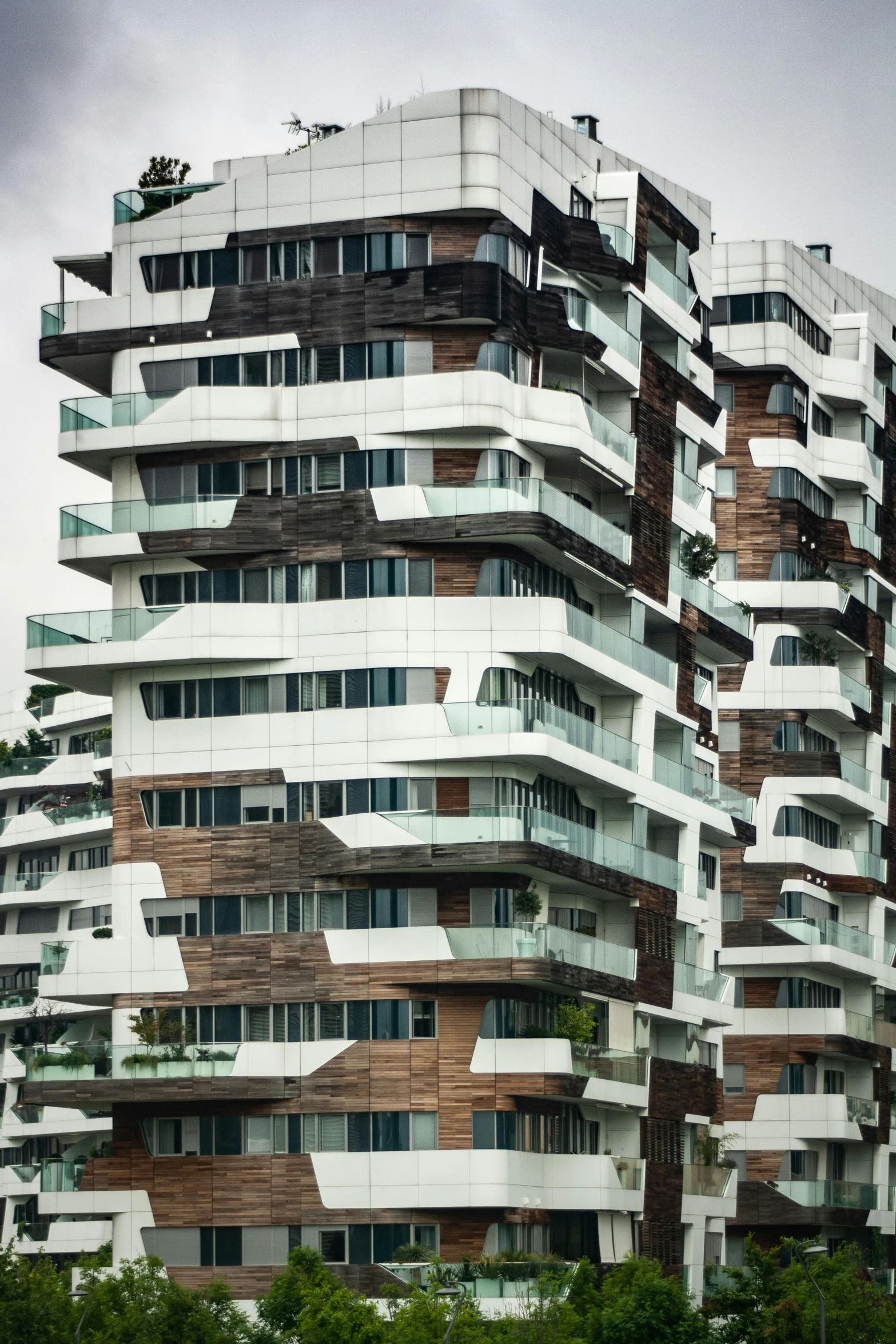 a tall building sitting on top of a lush green field, by Karel Dujardin, modernism, crenellated balconies, twisting streets, singapore, wooden houses