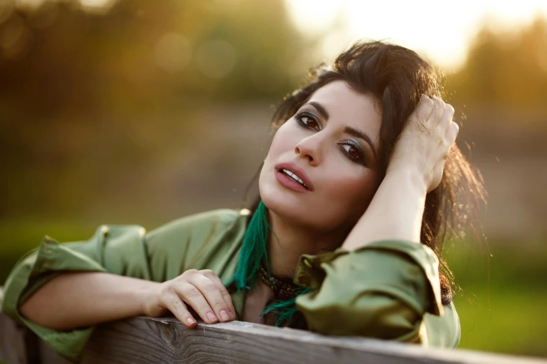 a woman sitting on top of a wooden bench, an album cover, sarah shahi, deep green, portrait image, shohreh aghdashloo