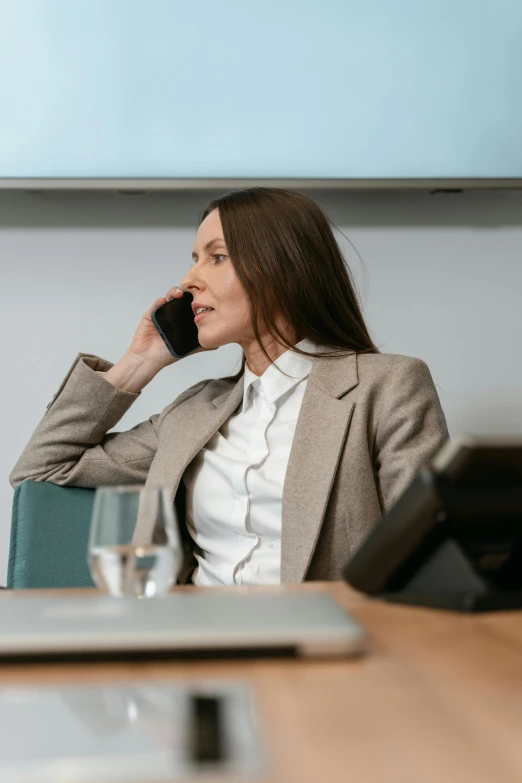 a woman sitting at a table talking on a cell phone, wearing a worn out brown suit, best practice, slightly minimal, multiple stories
