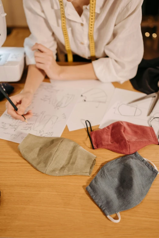 a woman sitting at a table in front of a sewing machine, a child's drawing, trending on pexels, wearing wooden mask, academic clothing, knolling, designer product