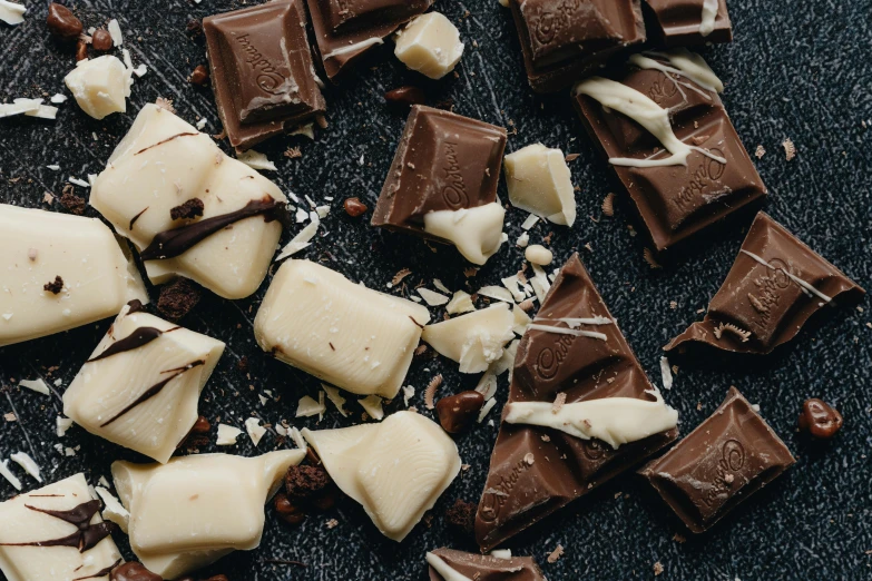 a bunch of pieces of chocolate sitting on top of a table, inspired by Nicolaes Maes, trending on pexels, slate, dark and white, vanilla, thumbnail