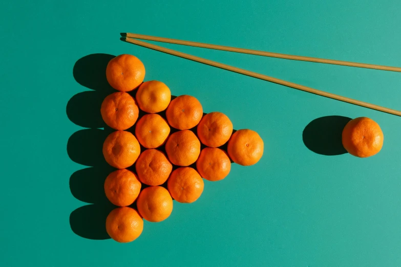 a pile of oranges next to a pair of chopsticks, inspired by Mike Winkelmann, kinetic art, floating spheres and shapes, rule-of-thirds, striking colour, trending on dezeen