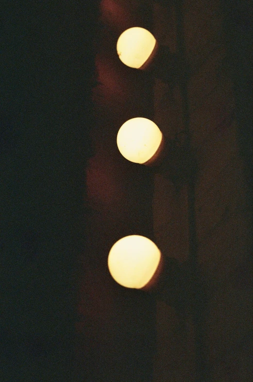 a row of lights hanging from the side of a building, an album cover, inspired by Elsa Bleda, unsplash, postminimalism, spheres, photo taken on fujifilm superia, lonely!! stop light glowing, close up shots