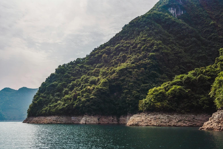 a boat in the middle of a large body of water, inspired by Tadao Ando, pexels contest winner, mingei, mountainous jungle setting, zezhou chen, cut into the side of a mountain, hasui kwase