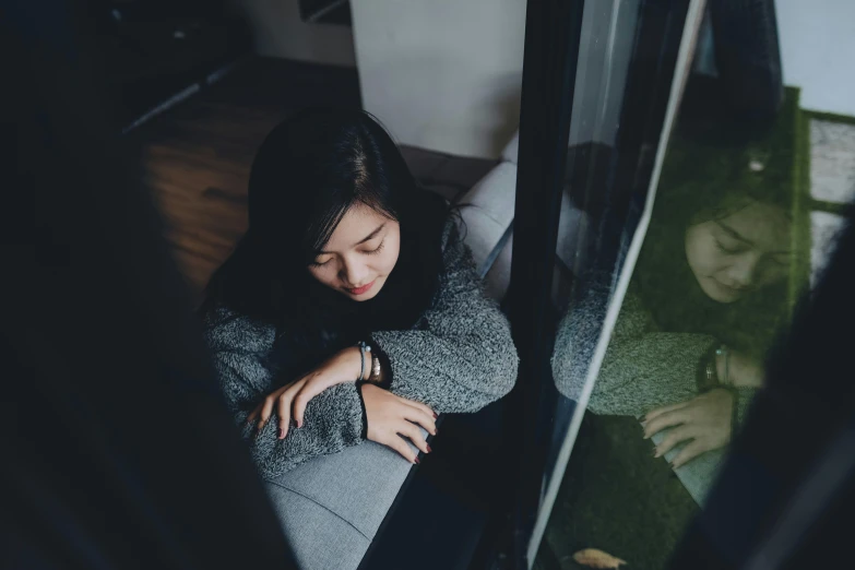 a woman laying on the floor with her eyes closed, a picture, inspired by Elsa Bleda, pexels contest winner, realism, looking through a window frame, young asian girl, disappointed, sitting on a couch