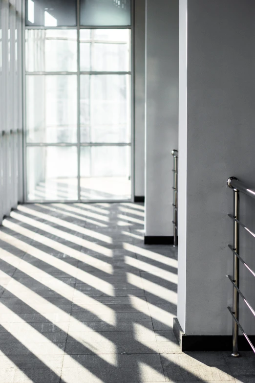 the sun shines through the windows of an office building, inspired by Pierre Pellegrini, unsplash, light and space, hallway, railing, silver light, high shadow