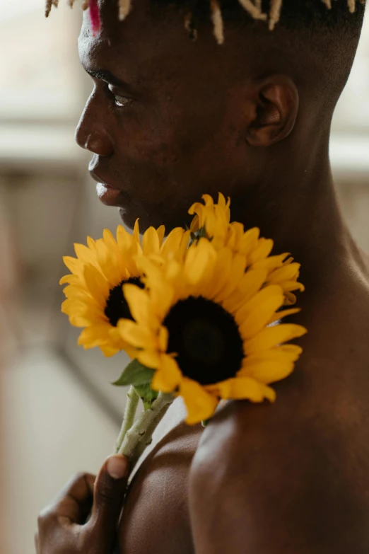 a man with dreadlocks holding a sunflower, inspired by Terrell James, trending on pexels, non binary model, shaved sides, dark brown skin, embrace