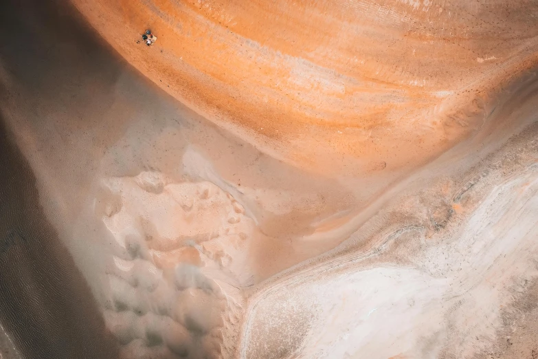 a man riding a surfboard on top of a sandy beach, a microscopic photo, trending on pexels, visual art, orange minerals, top down extraterrestial view, in a large desert cave, australian desert