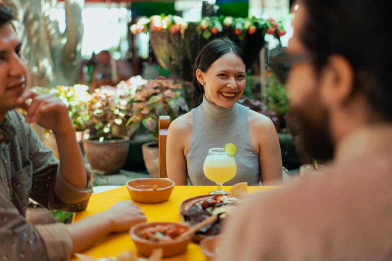 a group of people sitting around a yellow table, she is mexican, profile image, restaurant, a still of a happy