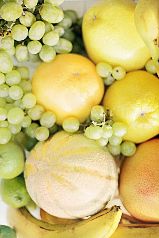 a basket filled with lots of different types of fruit, light yellow, up close, light greens and whites, 王琛