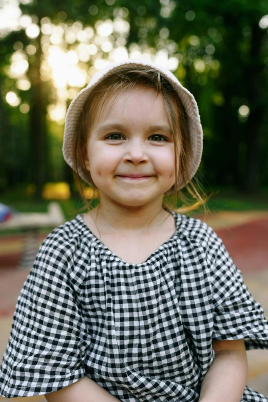 a little girl sitting on a skateboard in a park, pexels contest winner, cute checkerboard sundress, it's wearing a cute little hat, headshot, square