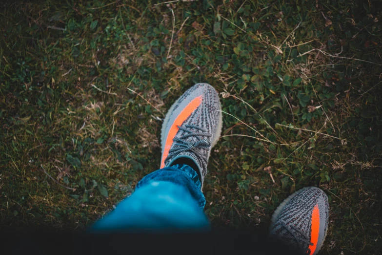 a person standing on top of a grass covered field, unsplash contest winner, renaissance, yeezy, high angle close up shot, grey orange, sitting in the forrest