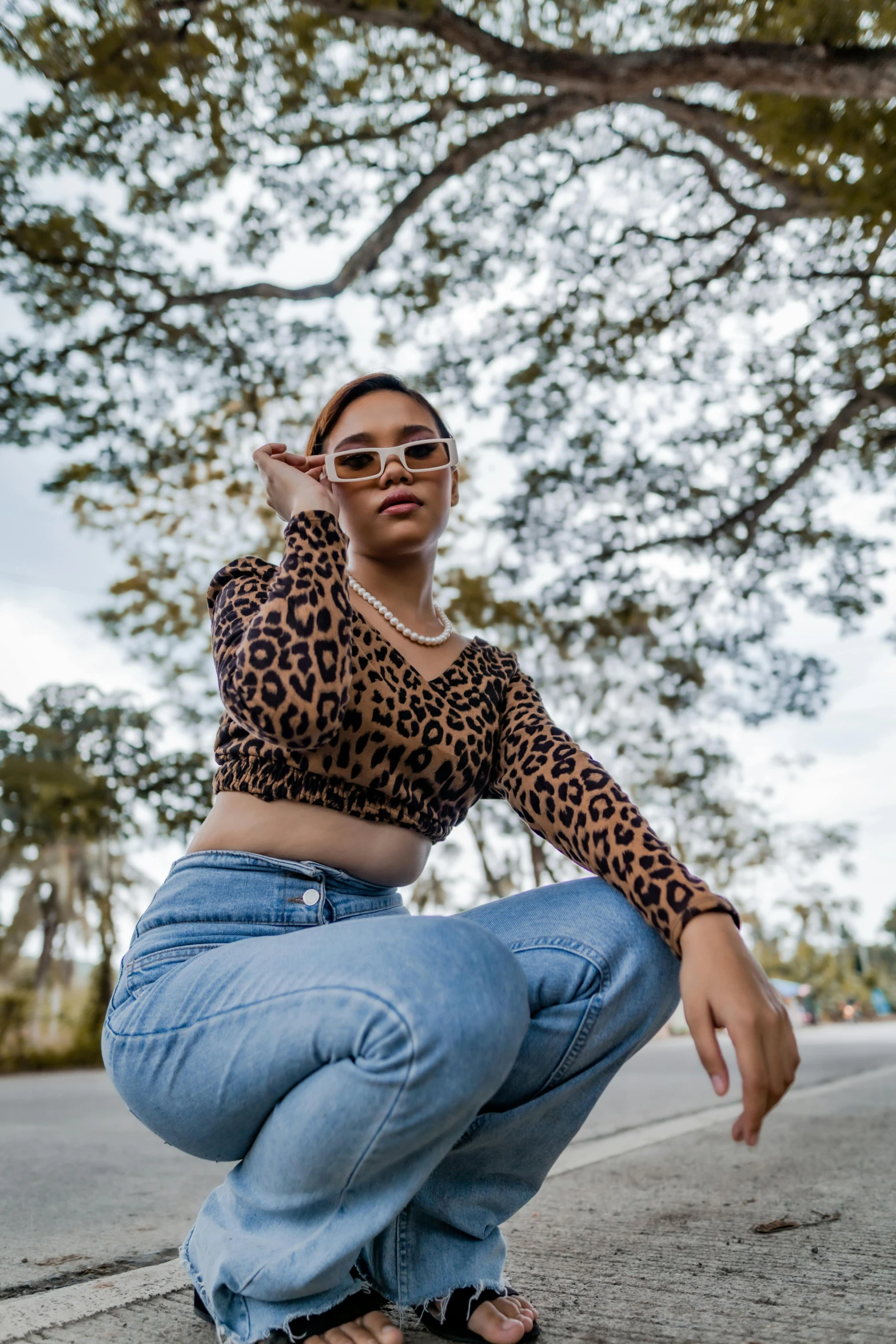 a woman squatting on the side of the road, an album cover, trending on pexels, wearing animal skin clothing, girl wearing round glasses, taken with sony alpha 9, light skin