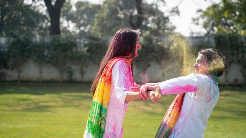 a couple of women standing on top of a lush green field, pexels contest winner, action painting, wearing a silk kurta, covered in white flour, multicoloured, game