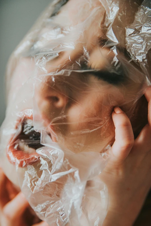 a woman in a plastic wrap covering her face, inspired by Elsa Bleda, pexels contest winner, busted crushed face, eating, close up of face, covered with organic flesh