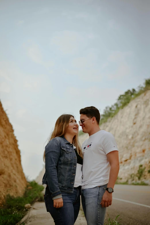 a man and woman standing next to each other on a road, a picture, pexels contest winner, over a chalk cliff, flirting smiling, wearing casual clothing, gif