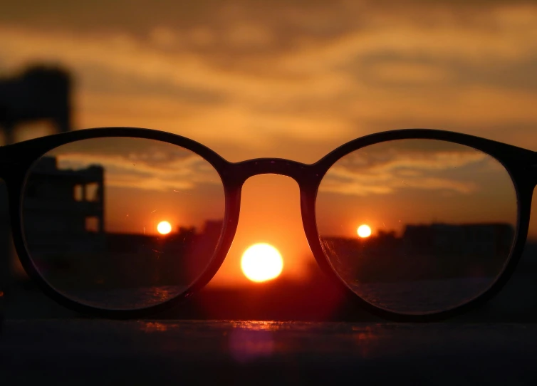 a pair of glasses sitting on top of a table, by Jan Rustem, pexels contest winner, sunset psychedelic, middle close up composition, enlightening, looking out