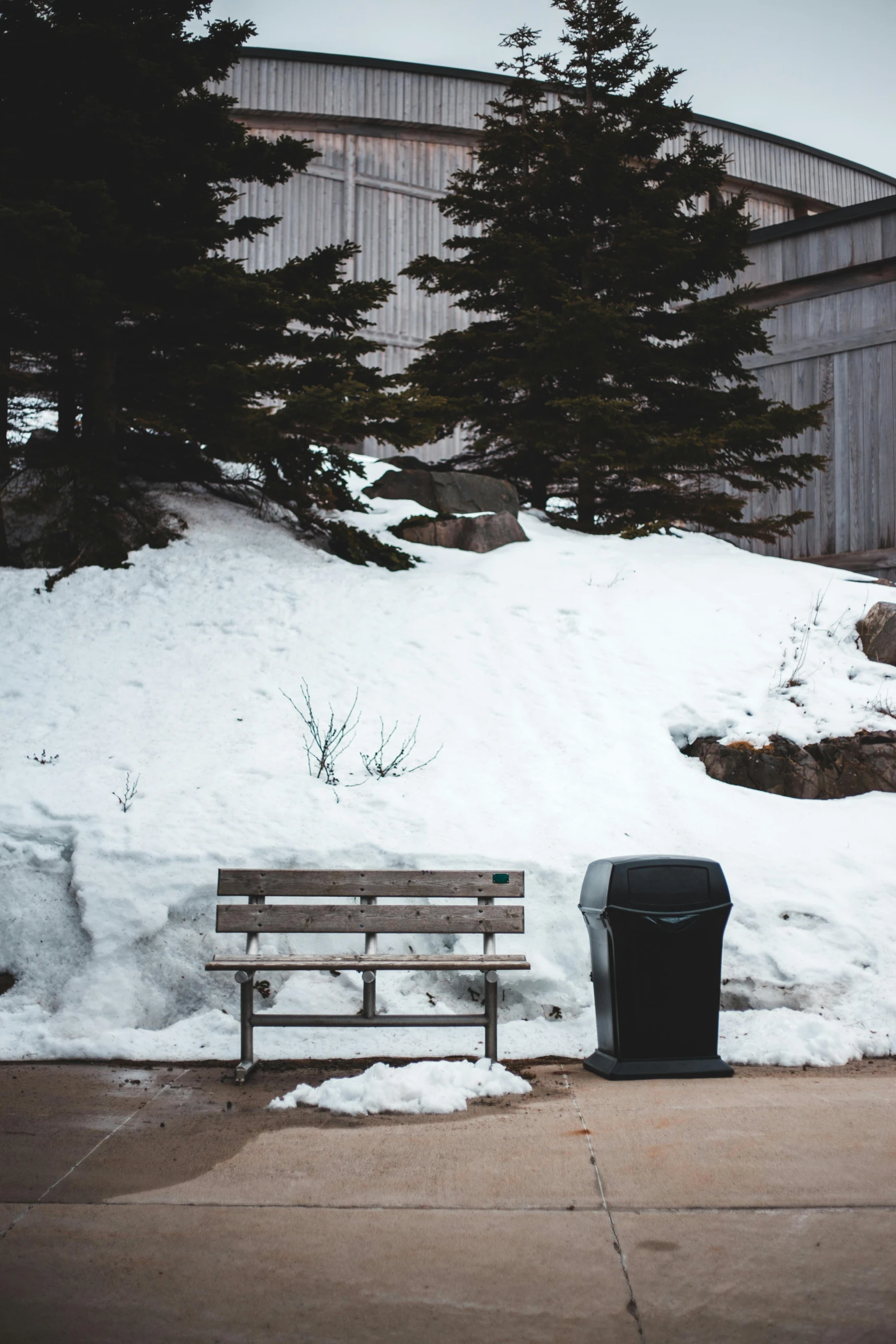 a wooden bench sitting next to a pile of snow, a picture, unsplash, postminimalism, trash can, a park, contain, sittin