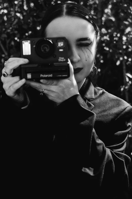 a woman taking a picture with a camera, a black and white photo, inspired by Diane Arbus, tumblr, realism, darkwave goth aesthetic, with fangs, !!! colored photography, warpaint aesthetic