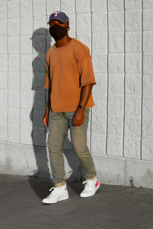 a man standing on a skateboard in front of a wall, inspired by Terrell James, wearing an orange t shirt, yeezy collection, warm and soft and subdued colors, view(full body + zoomed out)