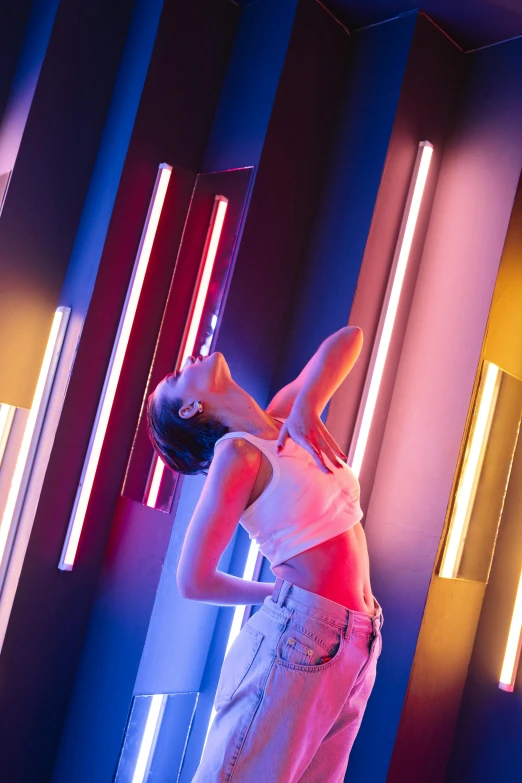 a woman standing in front of a wall with neon lights, inspired by David LaChapelle, pexels contest winner, light and space, playful pose of a dancer, with cinematic colour palette, dan flavin, brightly lit room