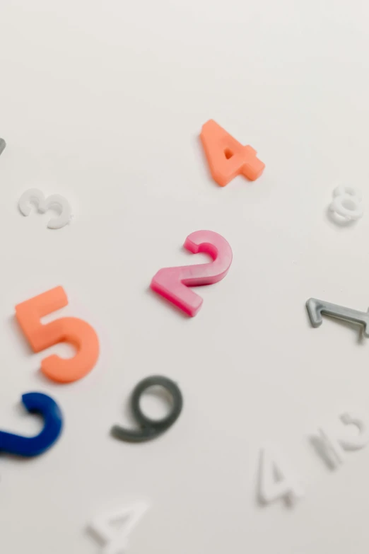 a close up of letters and numbers on a table, trending on unsplash, set against a white background, random colors, thumbnail, multiple stories