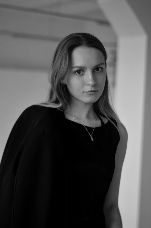 a black and white photo of a woman in a cape, inspired by Anna Füssli, hyperrealism, wide forehead, olya bossak, she is wearing a black dress, looking serious