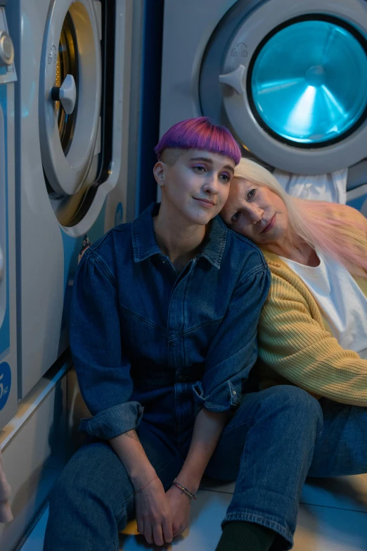 a man and a woman sitting in front of a washing machine, an album cover, antipodeans, cyberpunk dyed haircut, in a movie still cinematic, lesbian embrace, [ cinematic