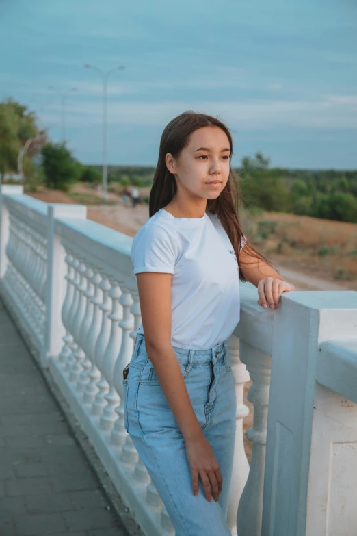 a woman standing on a bridge next to a body of water, by Andrew Stevovich, pexels contest winner, realism, portrait of white teenage girl, 15081959 21121991 01012000 4k, jeans and t shirt, isabela moner