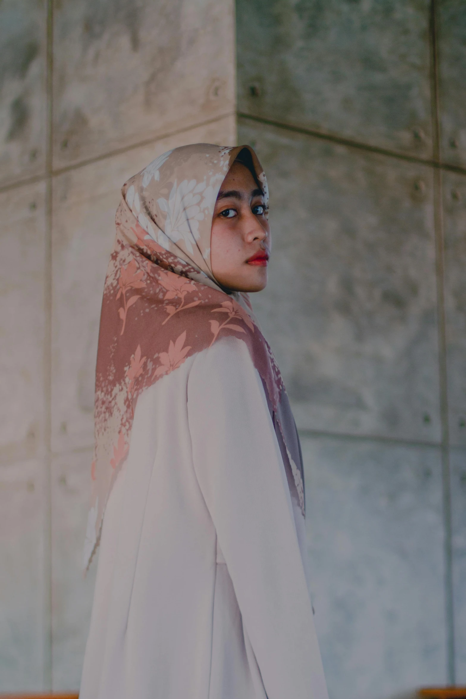 a woman wearing a hijab standing in front of a wall, by Basuki Abdullah, unsplash contest winner, delicate patterned, square, portrait soft low light, white and pink