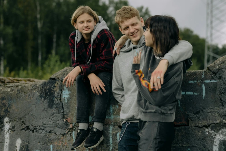 a group of young people sitting on top of a wall, by Jaakko Mattila, pexels contest winner, portrait of family of three, yung lean, 15081959 21121991 01012000 4k, fire