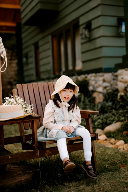 a little girl sitting on a bench next to a cake, inspired by Kate Greenaway, unsplash, ulzzang, sitting on designer chair, wearing farm clothes, outdoors