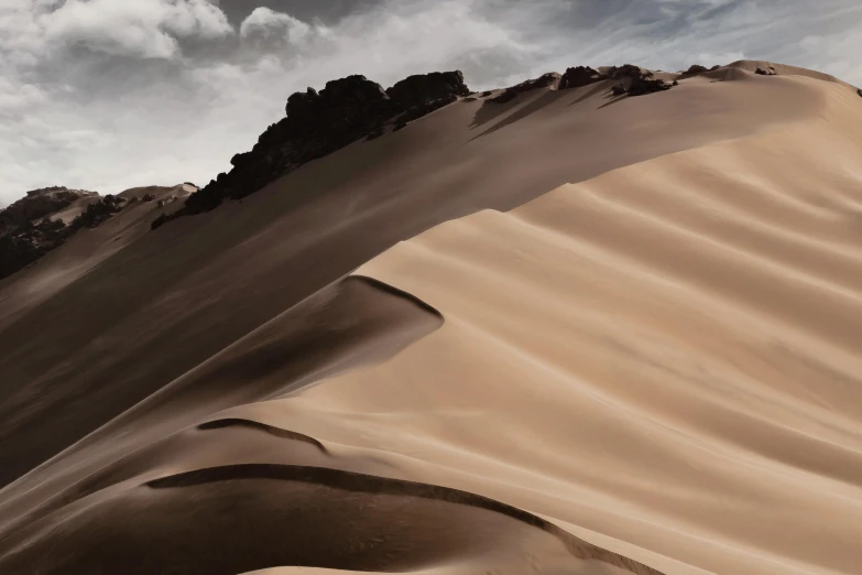 a person riding a snowboard on top of a sand dune, a matte painting, by Daniel Seghers, unsplash contest winner, peru, beige and dark atmosphere, sinuous, grey